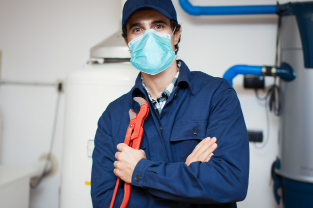 smiling-technician-repairing-hot-water-heater-wearing-mask-coronavirus-concept_53419-9260